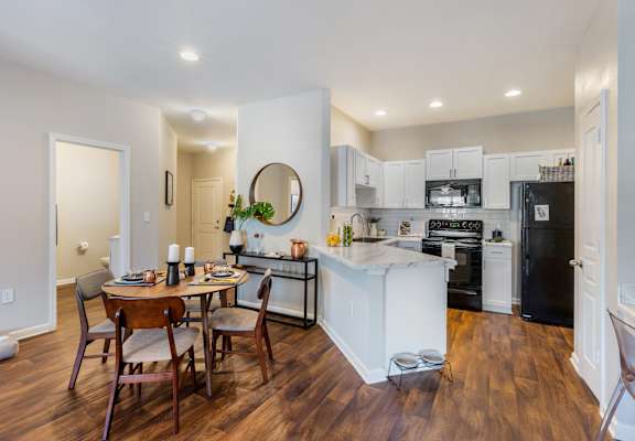 a kitchen and dining area with white cabinetry and black appliances