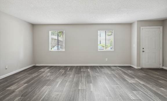 the living room of an empty house with wood floors and a door