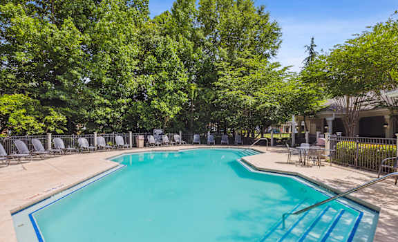 a resort style pool with chairs around it and trees