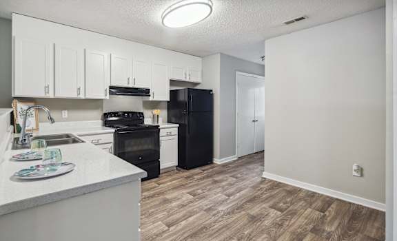 an empty kitchen with white cabinets and a black refrigerator