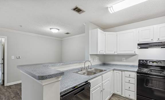 an empty kitchen with white cabinets and black appliances