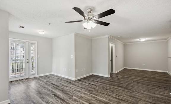 an empty living room with a ceiling fan and a window