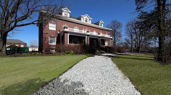 an old brick house with a gravel pathway in front of it