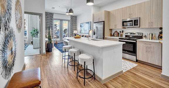 an open kitchen with a large white island and stools