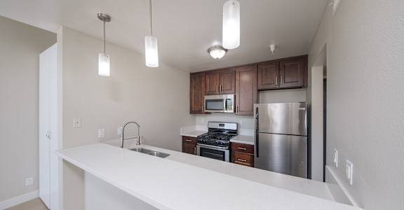 a kitchen with a white counter top and a stainless steel refrigerator
