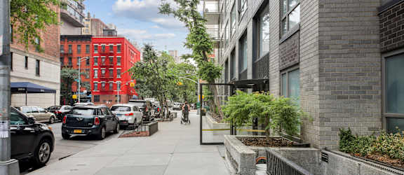 A city street with cars parked on the side and buildings in the background.