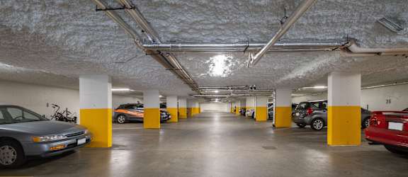 A parking garage with cars parked and yellow poles.