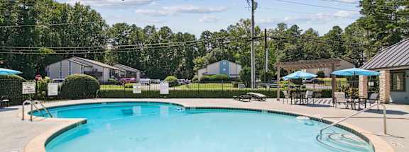 A round swimming pool with a blue umbrella above it.