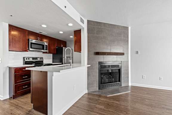 A modern kitchen with a fireplace and wooden floors.