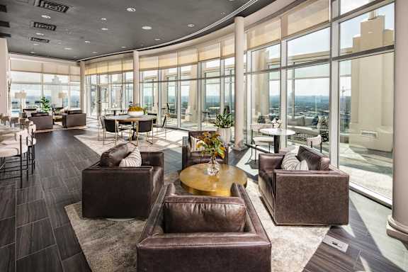 a living room with leather chairs and tables and large windows
