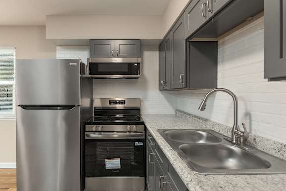A modern kitchen with a stainless steel refrigerator and oven.