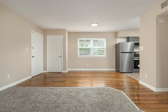 A kitchen area with a refrigerator, cabinets, and a window.