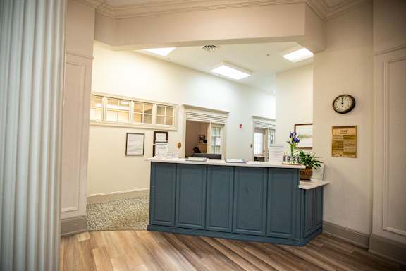 A reception area with a blue counter and a clock on the wall.