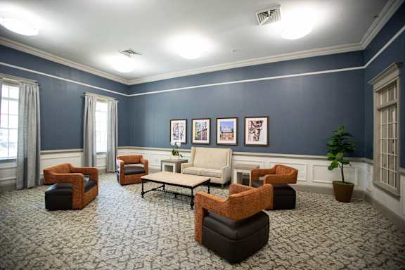 A living room with a patterned carpet and a variety of seating options.