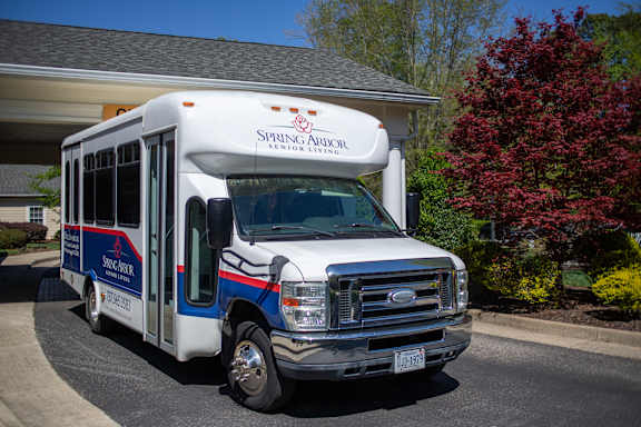 A white bus with blue and red stripes is parked in front of a building.