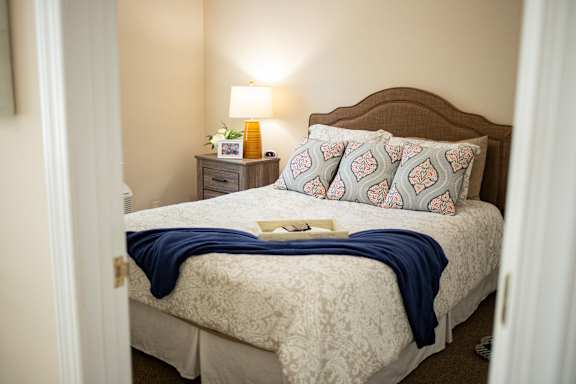 A bed with a blue blanket and a book on it.
