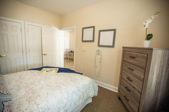 A bedroom with a bed, dresser, and two pictures on the wall.