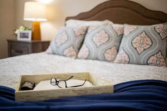 A pair of glasses sits in a wooden box on a bed.