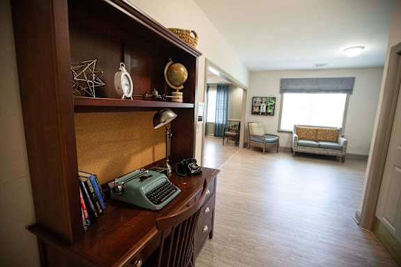 A room with a desk and chair with a typewriter on it.