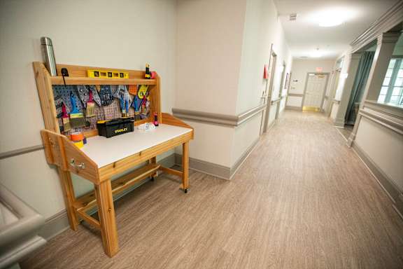 A long hallway with a bench and a table with various items on it.