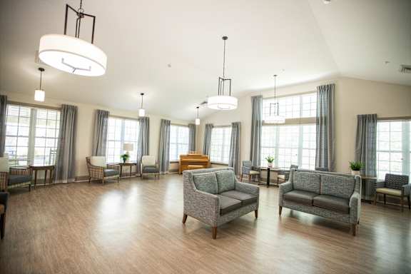 A spacious living room with grey couches and wooden floors.