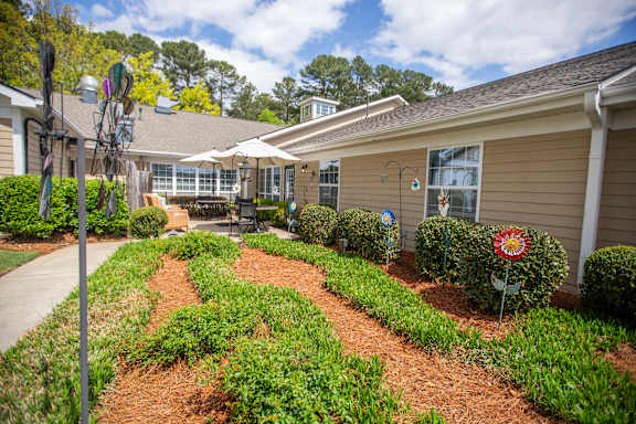 A garden in front of a building with a red and white flower.at Spring Arbor of Wilson, North Carolina