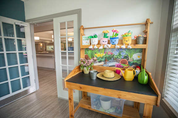 A wooden shelf with various potted plants and gardening tools.at Spring Arbor of Wilson, Wilson North Carolina