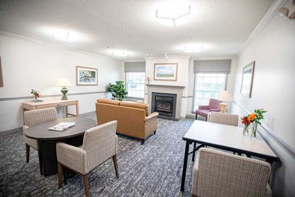A living room with a fireplace and a dining table.at Spring Arbor of Wilson, Wilson