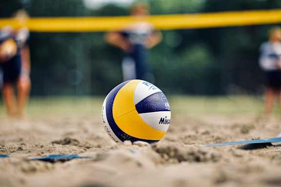 A blue and yellow beach volleyball with the word "Mikasa" on it is in the foreground.