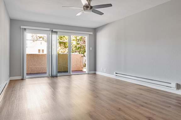 A room with a ceiling fan and sliding glass doors.