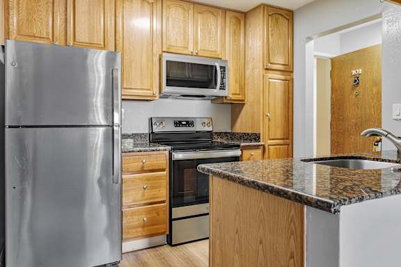 A kitchen with wooden cabinets and a granite countertop.