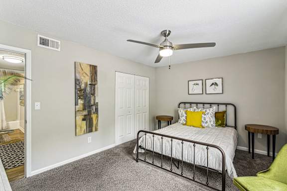 A bedroom with a bed, a chair, and a painting on the wall.