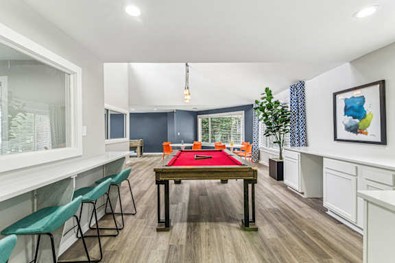 A room with a pool table and chairs.