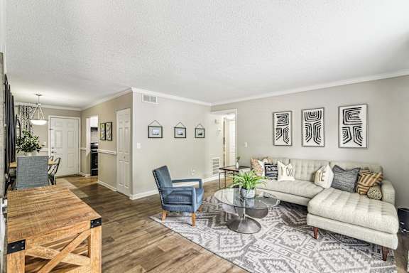 A living room with a couch, chairs, and pictures on the wall.