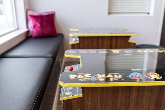 A skateboard with the word "PAC-MAN" on it is leaning against a wooden surface.