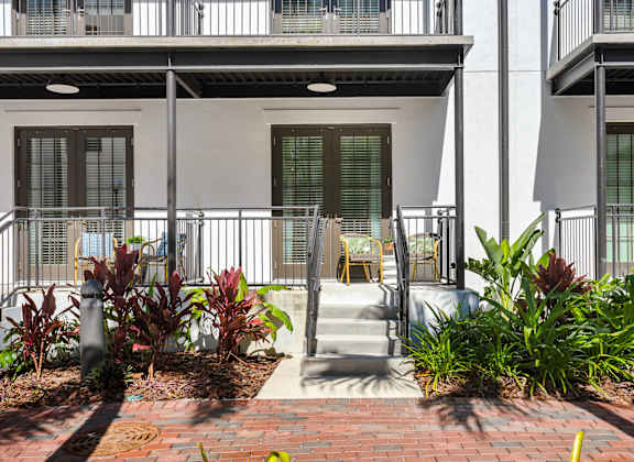 A white building with a balcony and a small garden in front.