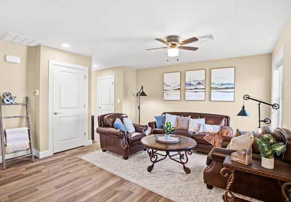 a living room with leather furniture and a ceiling fan