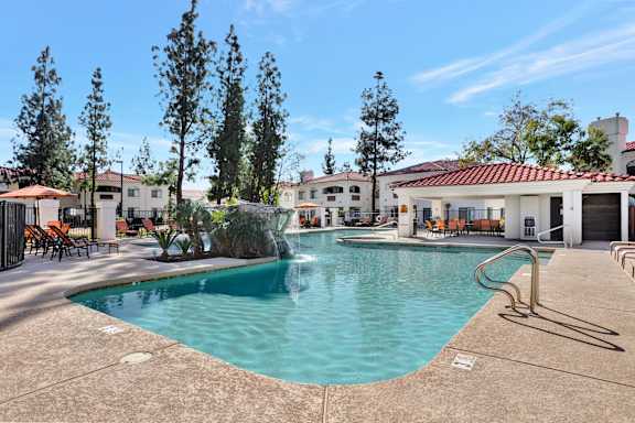 A large swimming pool surrounded by trees and buildings. at San Montego Apartments, Mesa, Arizona