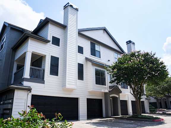 A white and black house with a tree in front.