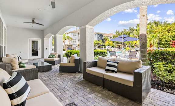 an outdoor patio with couches and chairs and umbrellas