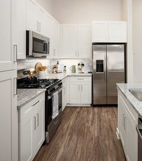 A kitchen with a stove, refrigerator, and sink.