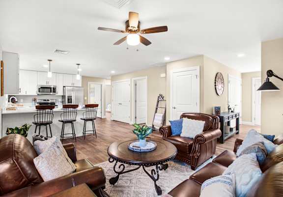 a living room with leather furniture and a kitchen in the background