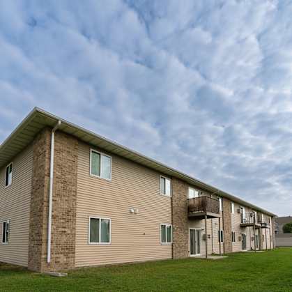 an apartment building with a cloudy sky in the background. Moorhead, MN Woodstone Apartments