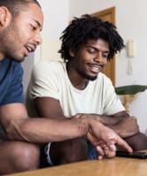 a hand holding a remote control in front of a television
