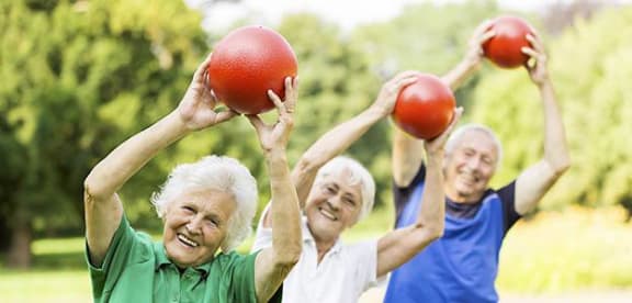 three older women holding up two red balls