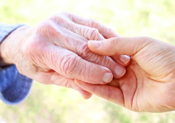 an older person holding the hand of a younger person