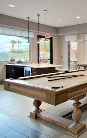 A pool table is in the middle of a room with a TV and a chair.