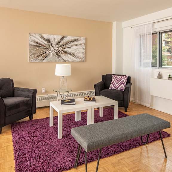 A living room with a grey couch, a round table, and a television.