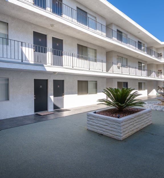 a courtyard with a fountain and a white building with black doors