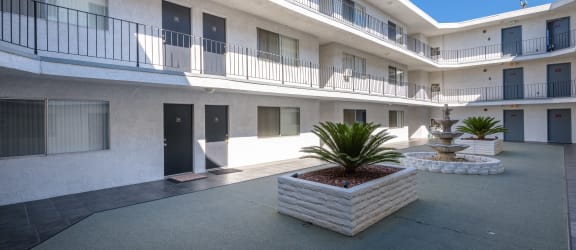 a courtyard with a fountain and a white building with black doors